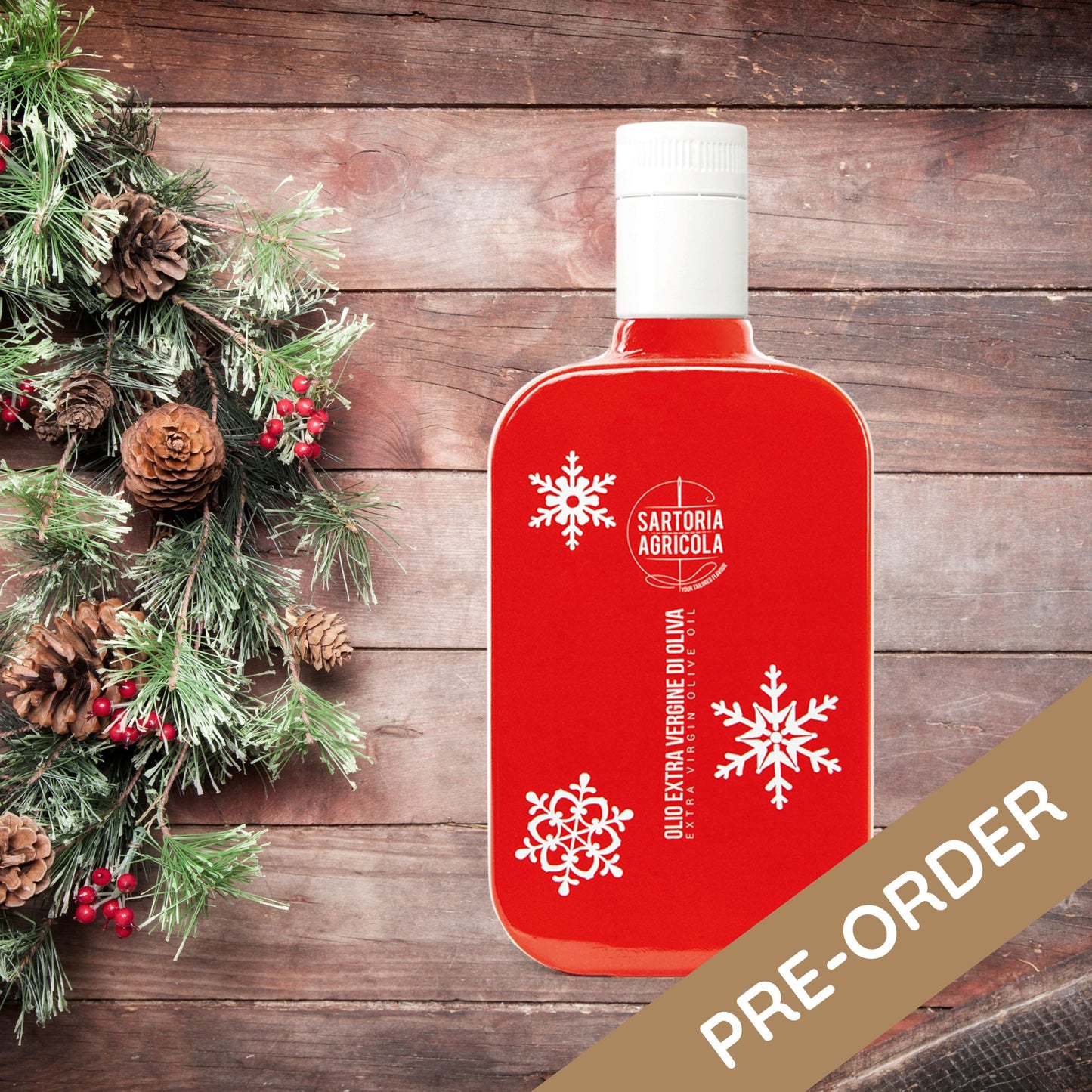 Red bottle of extra virgin olive oil, Christmas limited edition crafted in Puglia, with white snowflake design on rustic wood background.