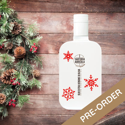 White bottle of extra virgin olive oil, Christmas limited edition crafted in Puglia, with white snowflake design on rustic wood background.