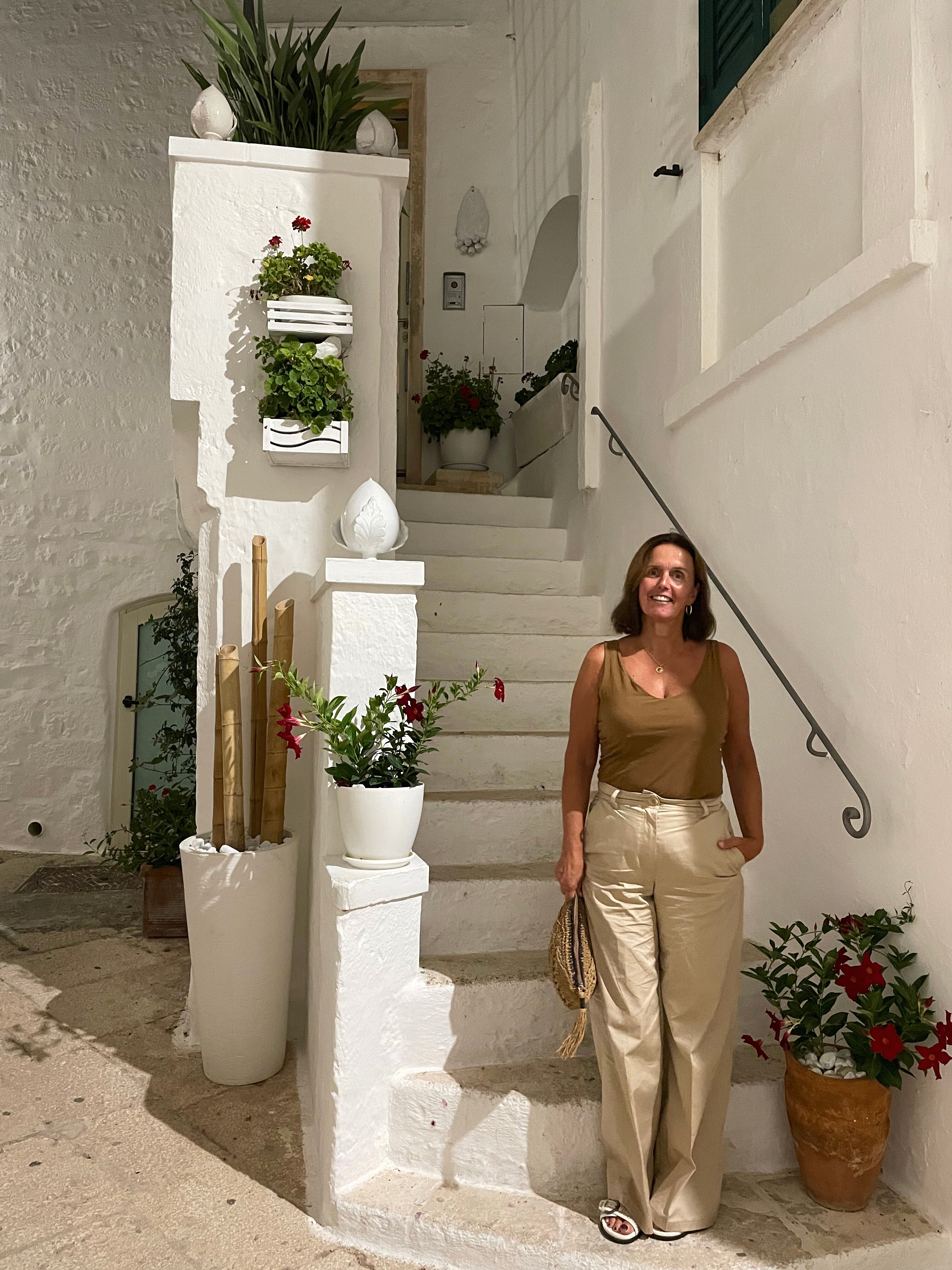 Hetty, oprichter van SOGNO by Hetty, in een wit straatje in Puglia – authentieke mediterrane sfeer en persoonlijke connectie met het merkverhaal